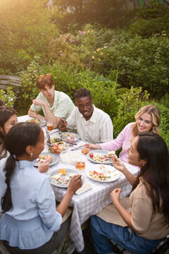 High angle view of male and female friends eating dinner at social gathering in back yard