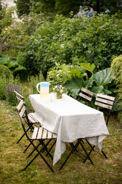 Dining table covered with tablecloth near empty chairs in back yard