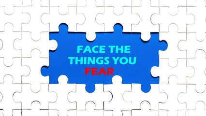 Fototapeta premium The concept of the writing FACE THE THINGS YOU FEAR in the middle of the puzzle with a beautiful blue background.