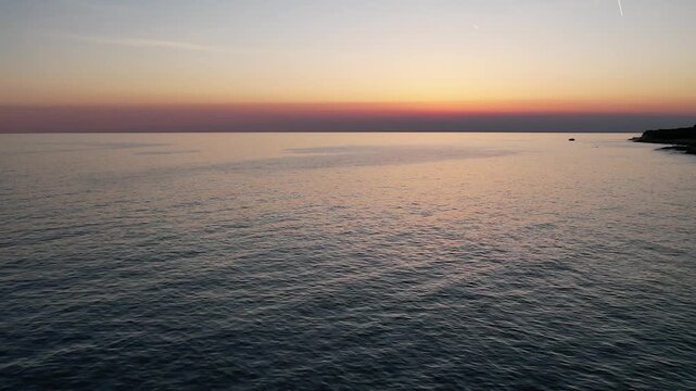 Breathtaking aerial drone view of Adriatic sea and Lanterna peninsula in Istria, Croatia during golden hour sunset, showing endless sea, horizon, coastline, turquoise waters.