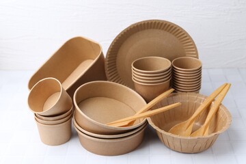 Set of disposable tableware on white tiled table, closeup