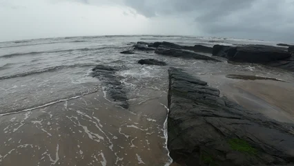 Fotobehang Bleke violet Moody and tranquil landscape of an evening beach, with a rocky shore and calm, misty ocean.  © sumit