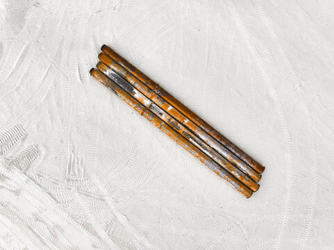Aerial view of parallel rusty metal rods lying on a white sandy surface, creating a stark contrast of textures and tones, Gulhi, South Male Atoll, Maldives.