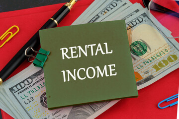 Economy and business concept. The inscription RENTAL INCOME on a green sticker on the background of dollar bills on the red book