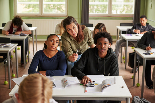 High angle view of female professor explaining math problem to students sitting at desk in classroom at school
