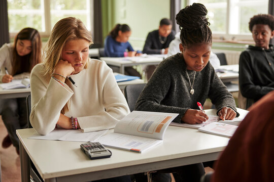 Focused female junior high students studying in classroom at school