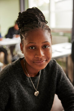 Portrait of smiling teenage girl with hair bun in classroom