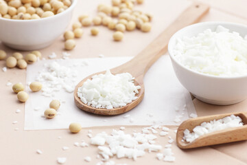 Soy wax with soybeans and fresh plant leaves on natural background, soy candles making and natural cosmetic ingredient  concept