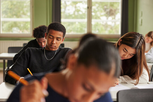 Teenage boy and girl giving educational exam in classroom at junior high school