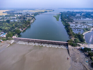 Aerial view of a water barrage with open gates and flowing water. 
The Muhuri Project, officially known as the Muhuri Irrigation Project (MIP), is a major water resource initiative in Bangladesh.