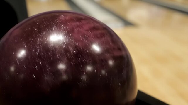 Polished maroon bowling ball with finger hole on a lane