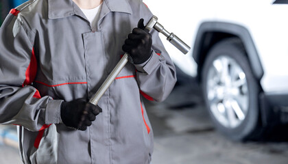 Replacement of winter and summer tires banner, auto mechanic in workshop holding wrench