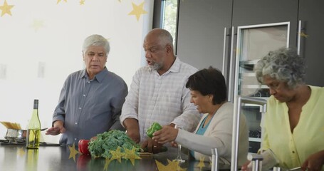 Senior man starting chopping kale at kitchen island sparking friends prepping peppers for food prep - Powered by Adobe