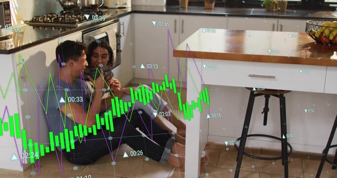 Man sipping mug as non-binary person tapping phone in kitchen showing animated finance chart data