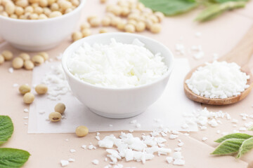 Soy wax with soybeans and fresh plant leaves on natural background, soy candles making and natural cosmetic ingredient  concept