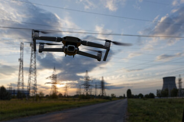 A quadcopter drone in flight against the blurred backdrop of a dramatic evening industrial landscape.