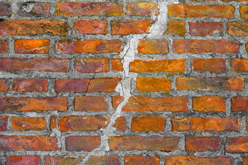 OLD BRICK WALL WITH VISIBLE DEEP CRACK COVERED WITH CEMENT GROUTING - Crack due to structural failure, subsidence or damage from earthquake