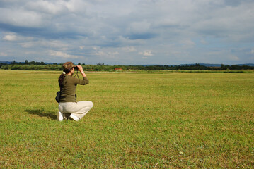 Woman looks around the countryside by using binoculars