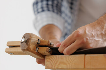 Male adult crafting leather belt with wooden tool in workshop