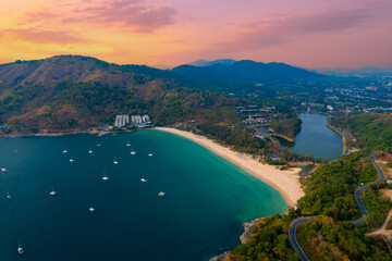Obraz premium Sunset view of Nai Harn Beach with vibrant seascape and boats in phuket, thailand