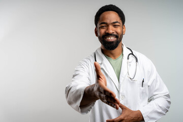 African young doctor smiling and shaking hands with patient in clinic, confident healthcare professional interaction