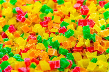 A close-up of a pile of candied fruit pieces. Sweet dried pineapple, orange, and papaya are used as fillings in confectionery and as an addition to breakfast muesli.