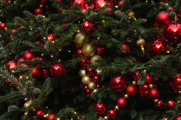 Details decorated Christmas tree with red, golden baubles and garland. Xmas card and pattern. Close up. Winter. Outdoor.