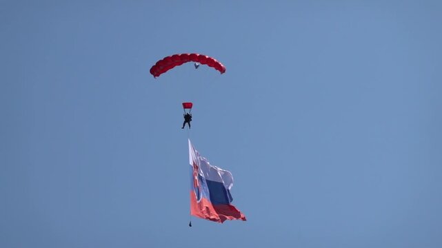 A military paratrooper glides with a Slovak flag unfurled, slow motion