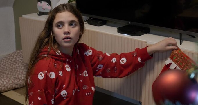 Daughter sitting on the floor, asking her mother where to put Father Christmas's boot. At home.