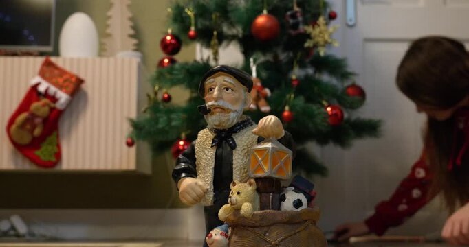 Close-up of the Christmas figure &lsquo;Olentzero&rsquo;. A girl picks it up and places it in front of the Christmas tree. 