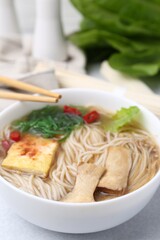 Tasty ramen with enoki and king oyster (eryngii) mushrooms on white table, closeup