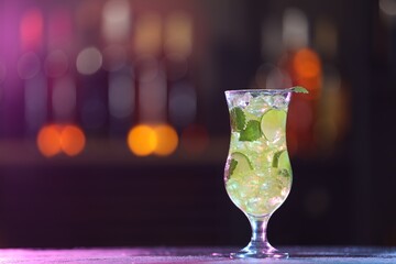 Glass of alcoholic cocktail on table against blurred background, space for text