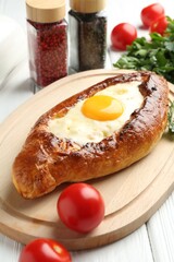 Tasty khachapuri with cheese, egg and other products on white wooden table, closeup