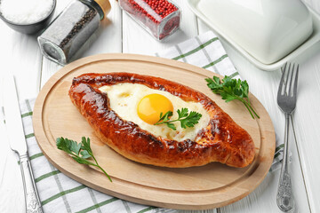 Tasty khachapuri with cheese and egg served on white wooden table, above view