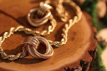 Beautiful gold earrings and chain on wood, closeup