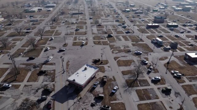  High-angle aerial shot of a deserted,  post-disaster town, showing residential streets, empty lots, and scattered vehicles, suggesting natural catastrophe, climate change impact, or urban a
