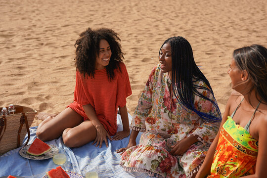 Group of happy african young women enjoy picnic with fresh watermelon and lemonade on the beach during summer time - Travel, vacation and holiday concept