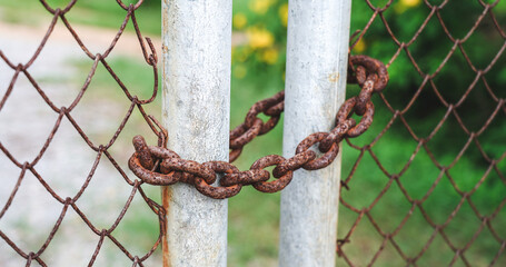 Locked rusted metal gate by rusty chain.