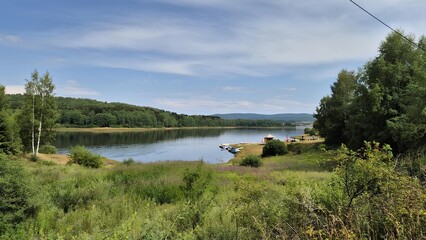 Scenic view of Vlasina Lake in Serbia with boats and forested hills in the background
