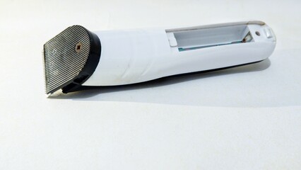 Electric hair trimmer isolated on white background, showing sharp metallic blades and textured...