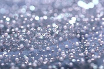 Detailed close-up of pearl light blue lace with sequins and beads on delicate mesh, creating a shimmering texture perfect for fashion, couture, and luxury fabric backgrounds