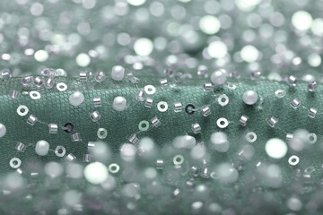 Detailed close-up of pearl mint green lace with sequins and beads on delicate mesh, creating a shimmering texture perfect for fashion, couture, and luxury fabric backgrounds