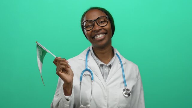 Woman smiling in white coat holding italian flag with stethoscope around neck against green background, showcasing multicultural and international medical theme.