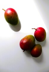 Beautiful and original composition with delicious ripe and tropical mangoes. Healthy and organic food concept. Photo with a white background and hard shadows. With space for text.