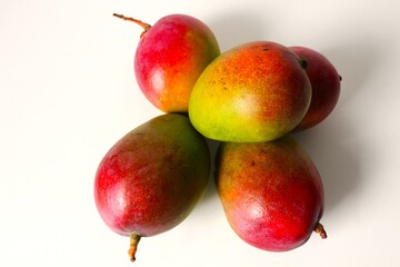 Beautiful and original composition with delicious ripe and tropical mangoes. Healthy and organic food concept. Photo with a white background and hard shadows. With space for text.