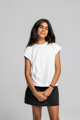 Teenage girl posing confidently in casual white t-shirt and black denim skirt, stylish fashion studio portrait.
