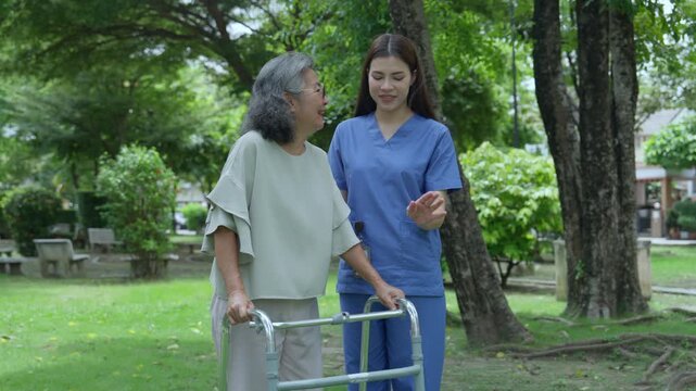 The caregiver is helping an elderly Asian woman rehabilitate her walking and monitor her condition after she underwent knee surgery, using treatment information from her doctor.