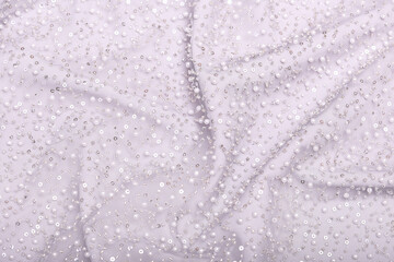 Close-up of elegant, off-white pearl lace fabric with delicate beads and sequins on fine mesh, creating a shimmering texture ideal for fashion, bridal, and luxury design concepts.