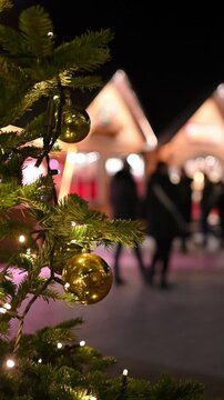 close up of christmas decorations on pine branches with soft focus market and people background