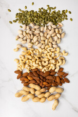 Overhead view of almond pistachio cashew nuts on light surface various